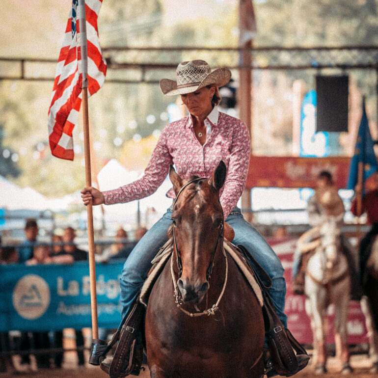 Femme à cheval qui porte fièrement le drapeau américain.