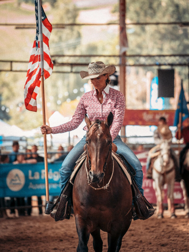 Femme à cheval qui porte fièrement le drapeau américain.